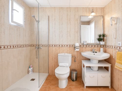 Modern bathroom at Apartamentos El Calón Playa with shower, toilet, sink, and wooden tile finishes in Cuevas del Almanzora