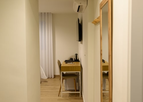 Habitación moderna del hotel Alcazaba Salobreña con escritorio de madera, silla, espejo y cortinas blancas en Salobreña