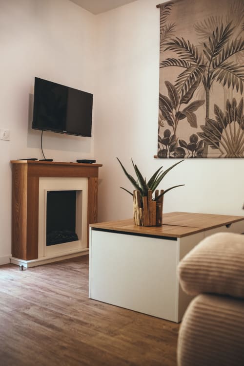 Espace de vie du cottage Les Tropiques avec télévision, mobilier en bois, décoration murale végétale tropicale et vue sur le jardin à Étretat