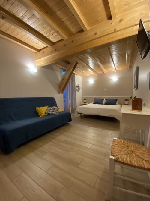 Chambre Chrysalide au Cocon De Curson : canapé bleu, lit queen-size, poutres apparentes et équipements modernes