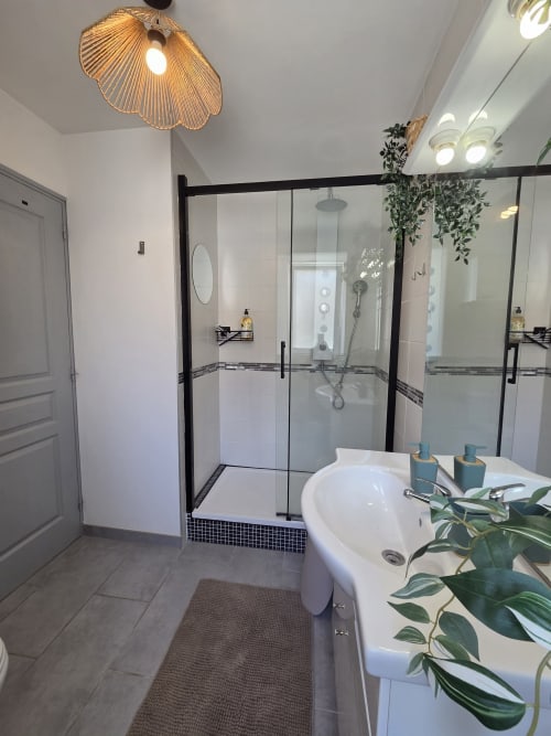 Salle de bain moderne à la Residence Cosy à Saint-Méen-le-Grand avec douche vitrée, lavabo blanc sur pied et éléments de qualité