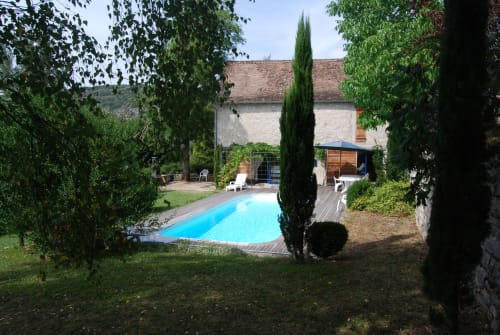 Piscine turquoise avec cyprès et maison en pierre aux Chambres d'hôtes Les Pratges, Figeac