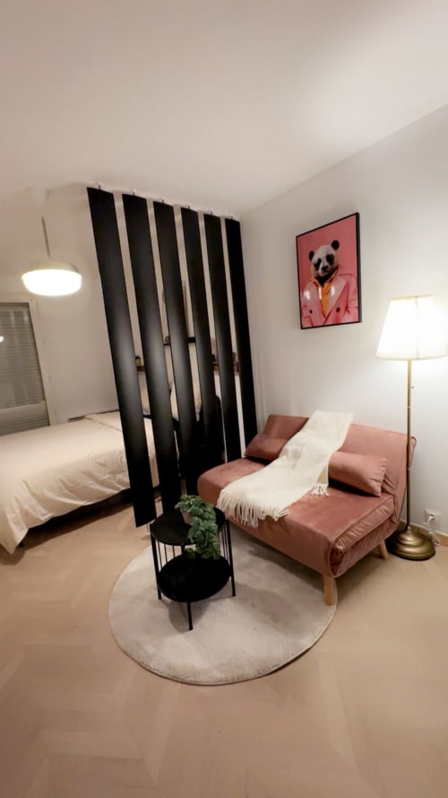 Appartement Cosy Luxe au Paradis Des Logis : lit, canapé rose, paravent noir et décoration panda