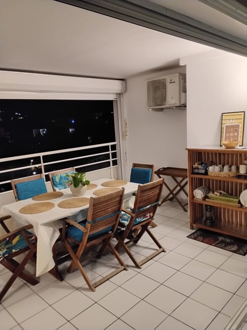 Espace repas sur balcon moderne de Kay Betty, Les Trois-Ilets avec vue mer, chaises bois et climatisation