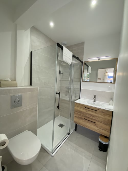 Salle de bain moderne du studio La Maison Blanche avec douche à l'italienne, meuble vasque en bois et carrelage en marbre