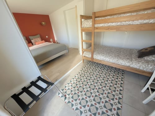 Chambre lumineuse au Logis de La Garenne avec lits superposés, lit simple, carrelage à motifs et vue sur le jardin