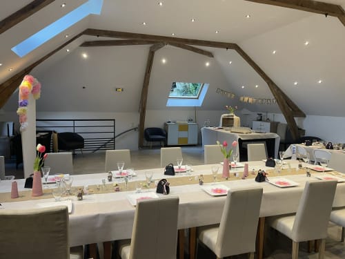 Elegant dining setup in La charretterie villa at Les Gites De Flaubert with long table, cream chairs, and pink floral décor