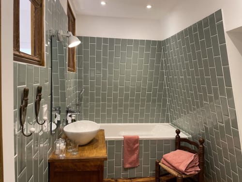 Salle de bain moderne du gîte Château de Vaux Morvan avec carrelage vert métro, vasque blanche et baignoire balnéo à Étang sur
