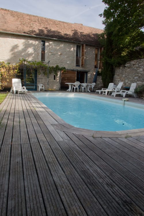 Piscine avec terrasse en bois aux Chambres d'hôtes Les Pratges à Figeac, transats et chaumière en pierre