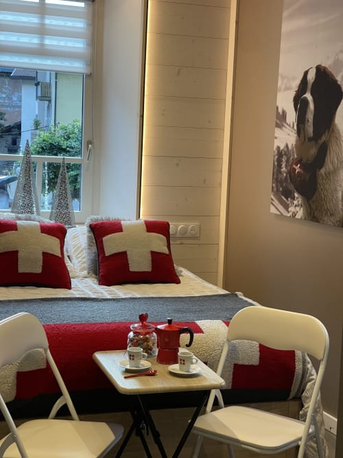 Chambre douillette à La Montagnette B&B à Moutiers, décor rouge et crème, coin détente et vue sur la ville