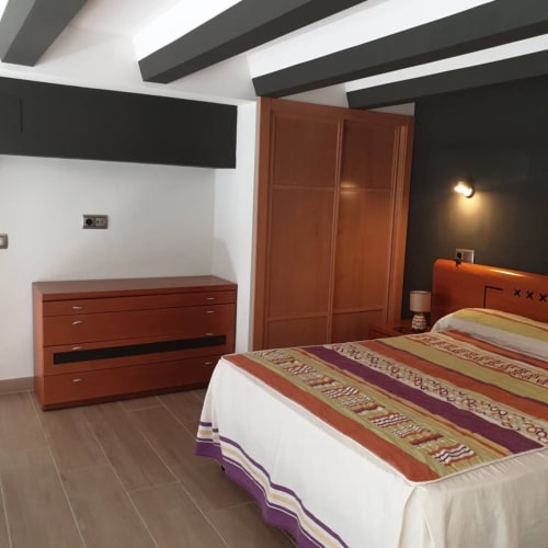 Dormitorio moderno en Hostal El Molino de Collado Villalba con muebles de madera, ropa de cama a rayas y vigas de techo contemporáneas