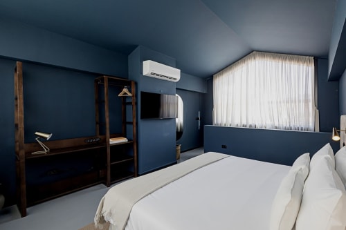 Moderno studio duplex de hotel no Porto com paredes azul-escuro, roupa de cama branca, móveis em madeira escura, TV de parede e vista para a cidade
