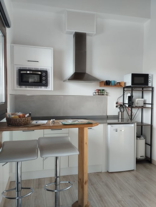 Cocina moderna en apartamento de Gueña, Cangas de Onís, con muebles blancos, encimera de madera, barra y acero inoxidable