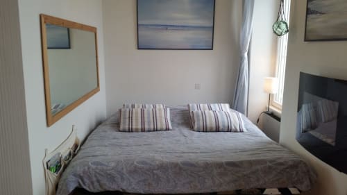 Chambre douillette à Mer et Maisons en Trinité-sur-Mer avec vue mer, coussins rayés, miroir en bois et lumière naturelle