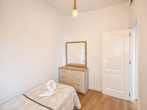 Bright bedroom at Apartamentos El Calón Playa with wooden dresser, mirror, and sea-view door in Cuevas del Almanzora