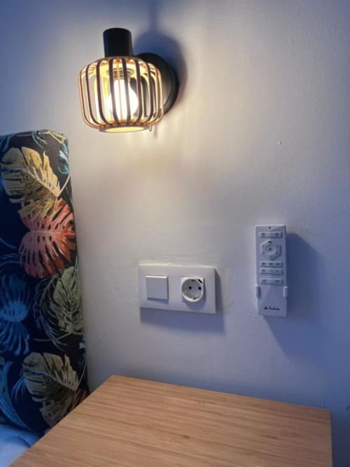 Rincón de apartamento moderno con lámpara colgante, interruptor de luz, enchufe y control remoto en pared blanca en Rural La Palma
