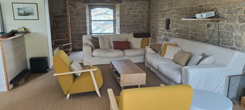 Spacieux salon villa Mer et Maisons avec chaises jaunes, canapés crème, table en bois et murs en pierre avec jardin