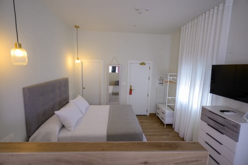 Habitación moderna en Hotel Alcazaba Salobreña con cama doble, cabecero gris, lámparas colgantes y TV con vistas a Granada
