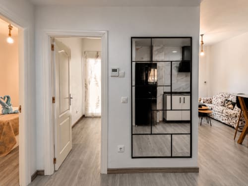 Interior moderno de apartamento en El Calón Playa con pasillo, espejo de marco negro, puertas blancas y sofá estampado en Cuevas del