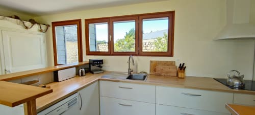 Cuisine moderne avec plans de travail en bois, armoires blanches et vue sur jardin à la villa Mer et Maisons à La Trinité sur Mer