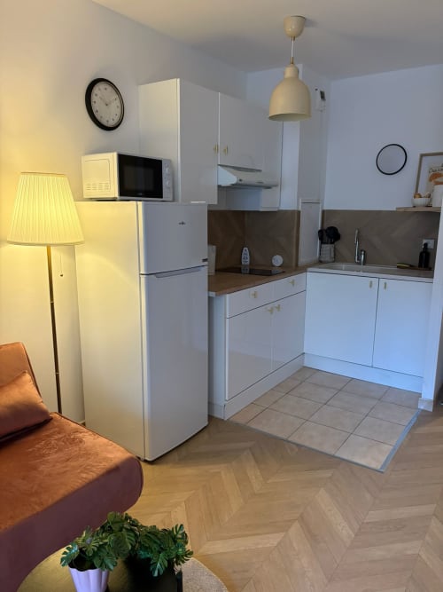 Cuisine moderne avec armoires blanches, crédence marron et électroménagers acier inoxydable à l'appartement Cosy Luxe du Paradis Des