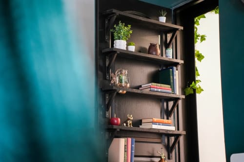 Étagères murales en bois avec livres, plantes en pot et objets de décoration dans l'appartement Escapade Chic aux Séjours Ardennais