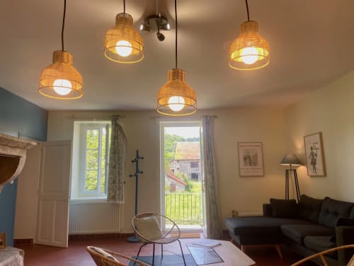 Des luminaires en tissage illuminent le salon du gîte au Château de Vaux Morvan, avec vue sur le jardin par les portes-fenêtres