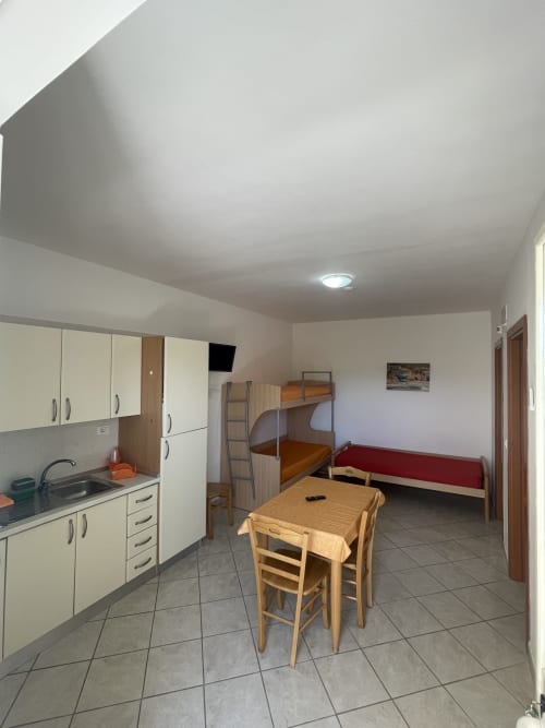 Appartamento Villa Angela a Vieste: angolo cottura, tavolo da pranzo, letti a castello e divano in moderno monolocale