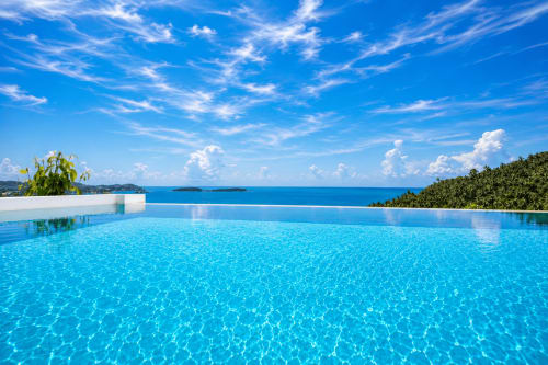 Luxury infinity pool overlooking turquoise sea at Indigo Villa Samui, Ko Samui Thailand with tropical forest and blue sky