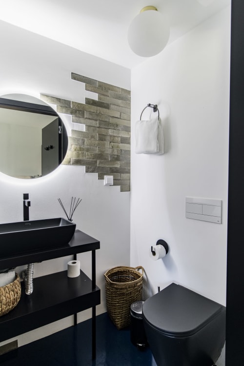 Banheiro moderno em quarto de hotel no Porto com pia preta, parede de destaque em pedra, paredes brancas e acabamentos minimalistas
