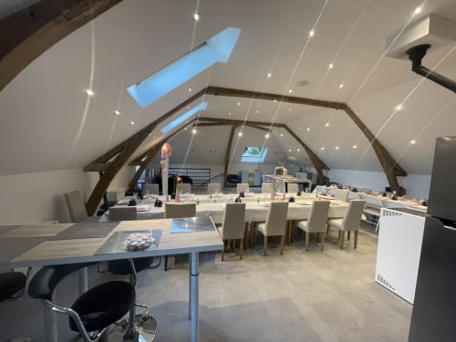 Modern loft workspace at Les Gites De Flaubert cottage with exposed beams, dining table, and skylight windows in Le Héron,
