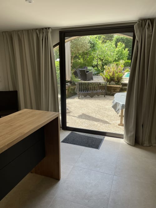 Le Loft cottage aux Pratges : portes-fenêtres ouvertes sur la piscine, mobilier de détente et vue sur le jardin