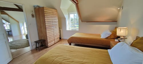 Chambre lumineuse de la villa Mer et Maisons avec deux lits, poutres en bois et vue sur le jardin à La Trinité sur Mer