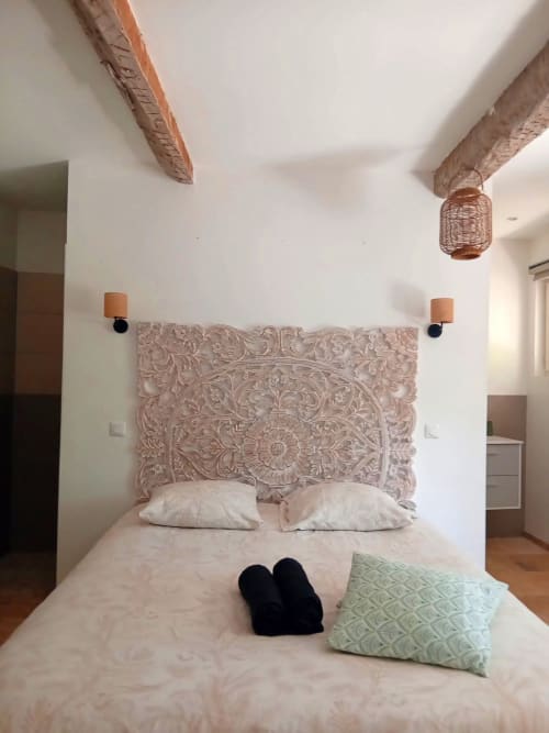 Chambre avec tête de lit en bois sculpté, plafond à poutres et draps blancs au gîte Chez Laure & Marc à Plaissan, France