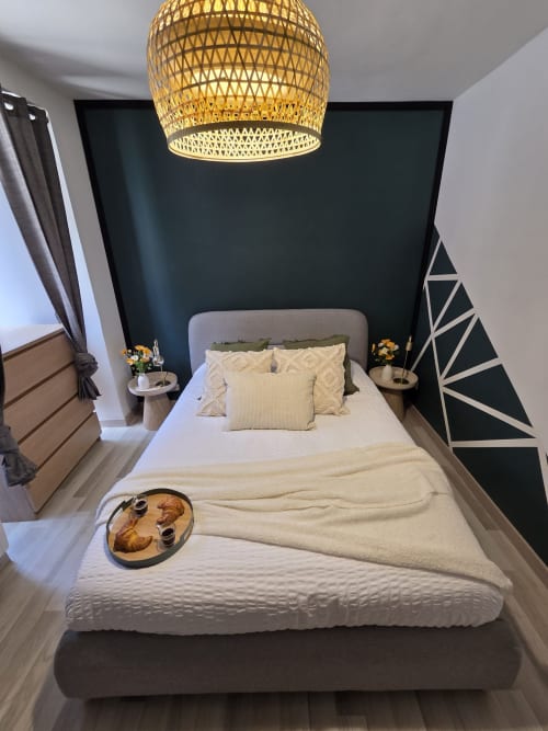 Chambre moderne à la Residence Cosy de Saint-Méen-le-Grand avec luminaire suspendu tressé doré, mur d'accent foncé et literie crème