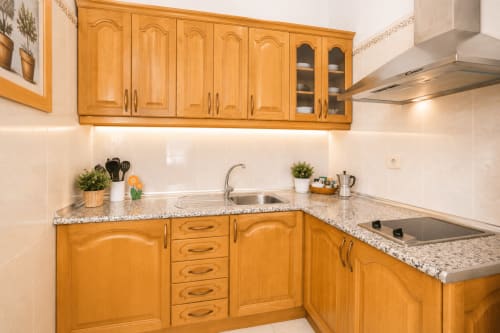 Cuisine moderne avec armoires en bois, plan de travail en granit et électroménagers inox dans un appartement de Corralejo près de la plage