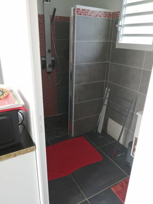 Salle de bain moderne avec douche carrelage noir, accents rouge et blanc au gîte Kaz A Bibi à Sainte-Rose, Guadeloupe