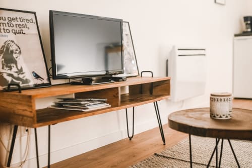 Salon moderne du gîte d'Étretat avec meuble TV en bois, téléviseur écran plat, table basse ronde et vue sur le jardin