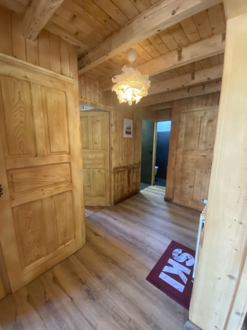 Wooden hallway with exposed beams in Chalet Les Georgières, Notre-Dame-de-Bellecombe, leading to multiple rooms with rustic