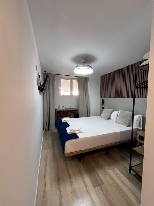 Habitación estándar moderna en Hostal Abacoa de Alicante con cama queen, escritorio, TV y vista a la ciudad