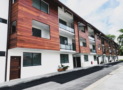 Immeuble moderne à Cayenne, Guyane avec revêtement en bois rouge et façade en brique blanche aux Maisons En Or
