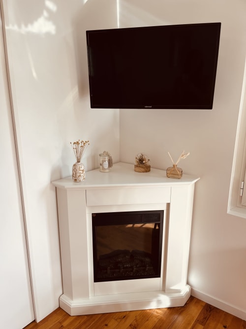 Cheminée d'angle blanche moderne avec télévision écran plat au-dessus dans le cottage Bobochic d'ART DE VOYAGER, Étretat