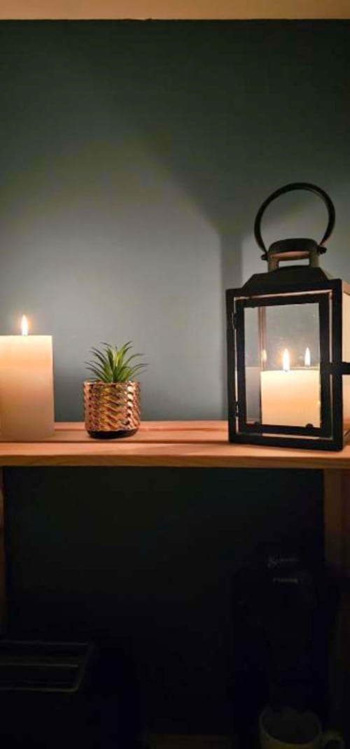 Étagère éclairée à la chandelle avec lanterne noire, bougies crème et plante succulente en pot aux Gîtes Saint Valery En Caux