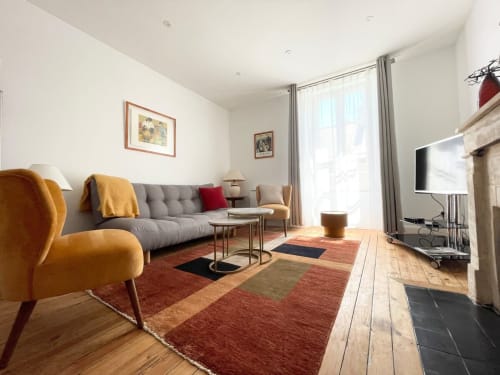 Salon moderne du Le 58 Bayeux avec canapé gris, fauteuil moutarde, cheminée et kitchenette à Bayeux, France