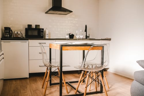 Cuisine-salle à manger moderne du gîte ART DE VOYAGER Étretat avec chaises transparentes, table en bois et meubles blancs