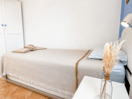 Bright bedroom at Apartamentos El Calón Playa with beige patterned bedspread, pillows, pampas grass decor, and white wardrobe