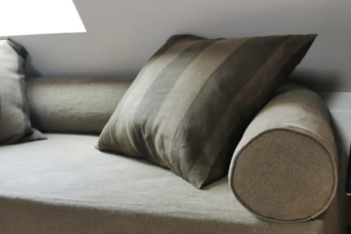 Elegant beige sofa with striped and cylindrical pillows in Fraternité Loft at Villa République Normandie, Caen