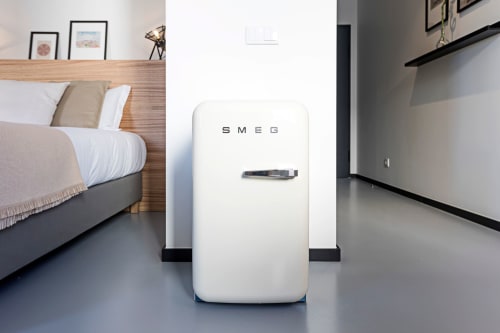 Moderno refrigerador branco SMEG na suíte Standard da coleção Benefit Collection do hotel em Porto, com cama e kitchenette visíveis