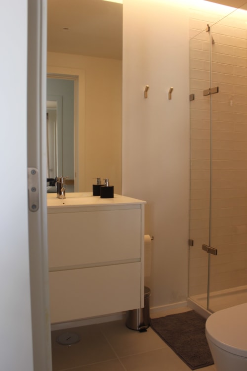 Modern bathroom with vanity sink, glass shower enclosure, and dark tile flooring at Break Lovers in Tavira, Portugal