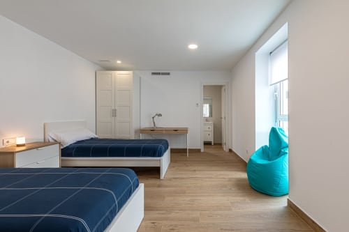 Spacious double bedroom at Residencia Demar in Godella with two beds, turquoise bean bag, desk, and natural light